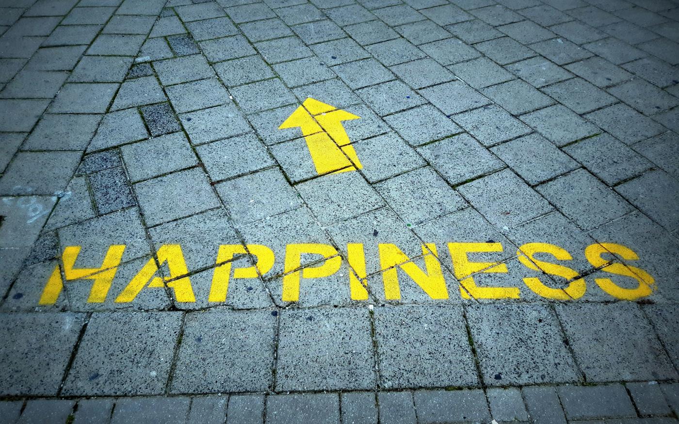 a brick sidewalk with a yellow arrow painted on it by D Jonez courtesy of Unsplash.