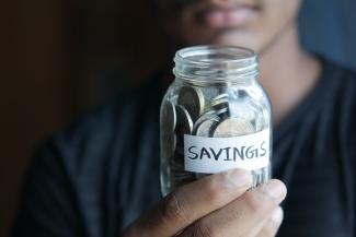 a man holding a jar with a savings label on it by Towfiqu barbhuiya courtesy of Unsplash.