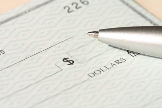 a pen sitting on top of a cheque paper by Money Knack courtesy of Unsplash.