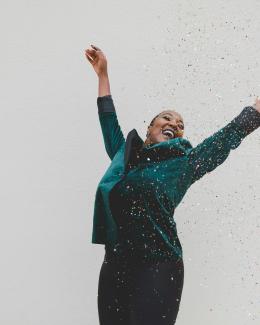 woman in green jacket raising her hands by Clay Banks courtesy of Unsplash.