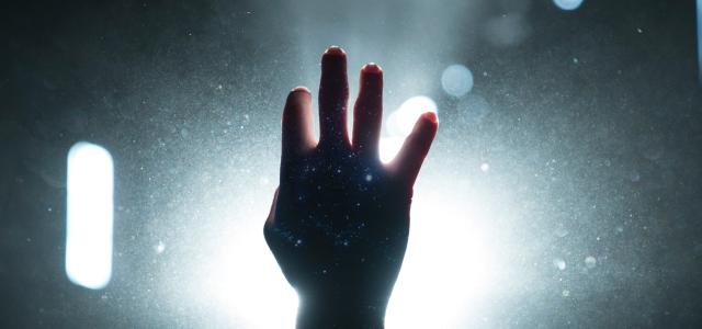 person's hand on light by Kyle Johnson courtesy of Unsplash.