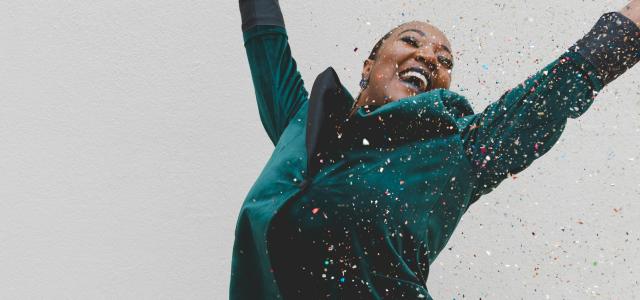 woman in green jacket raising her hands by Clay Banks courtesy of Unsplash.